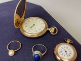 trois bagues, une montre, une bague, une bague et une bague posées sur un tissu bleu