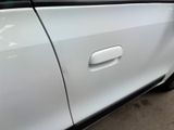 a white car with a door handle on the side of the road