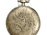 a silver pocket watch with a floral design on it