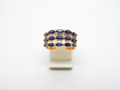 un gros plan d'une bague ornée de pierres bleues sur un fond blanc