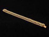 a close up of a gold chain bracelet on a black background
