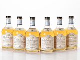 quatre bouteilles de whisky sont alignées sur une surface blanche