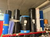de nombreux rouleaux de plastique noir sur une étagère dans un entrepôt