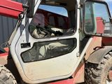a red and white tractor parked in the dirt