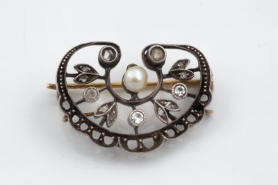 a pearl and diamond broochle on a white surface