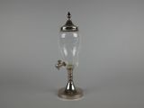 un ancien distributeur d'eau en verre plaqué argent, posé sur un socle
