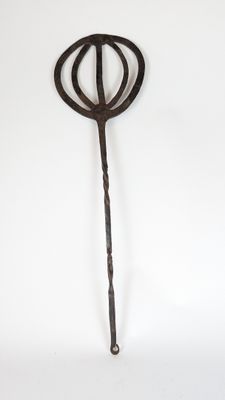 a metal object with a long handle on a white surface