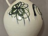 un vase blanc orné d'un motif noir et vert
