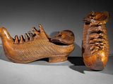 pair of carved shoes and a wooden shoe stand on a gray surface