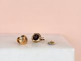 two pairs of gold and garnetite stud earrings on a marble block