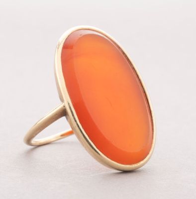 a close up of a ring with an orange stone in it