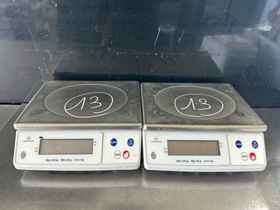 two electronic scales sitting on top of a metal counter top