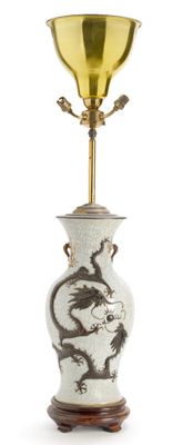 un vase blanc orné d'un dragon, surmonté d'une coupe dorée