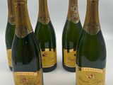four bottles of champagne are lined up on a white surface