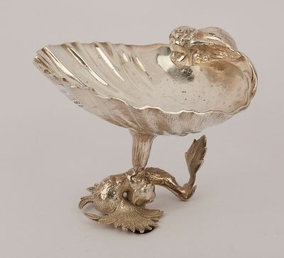 an antique silver plate with a bird on top of it