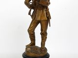 statue en bronze représentant un soldat tenant un fusil, posée sur un socle noir