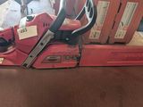 une tronçonneuse rouge posée sur une table en bois
