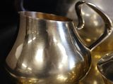 a silver plate with a silver pitcher and a silver cup on it