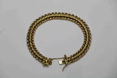 gros plan d'un bracelet en or sur une surface blanche