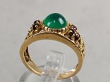 a close up of a gold ring with a green stone on it