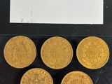 six gold sovereigns are on display in a glass case