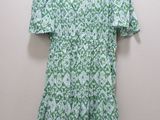 une robe à fleurs verte et blanche suspendue à un cintre