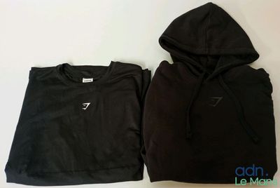 un sweat à capuche noir et un haut court noir posés sur une table blanche