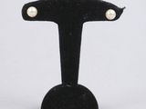 une paire de boucles d'oreilles à clous en perles, posée sur un socle en velours noir