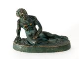statue of a man sitting on a base with his foot on the ground
