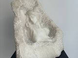 a white sculpture of a dog in a bed on a black table