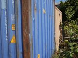 a blue shipping container sitting in the middle of a yard