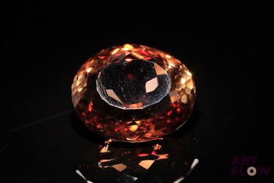 a close up of an orange diamond on a black surface