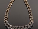 a gold and silver necklace with a chain on a black surface