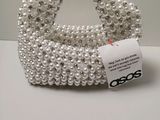 a close up of a white beaded purse on a table