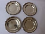 four silver plates on a white table with a white background