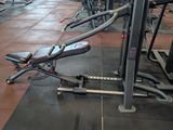 rows of stationary exercise machines in a gym room with tile flooring