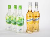 quatre bouteilles d'alcool sont alignées sur une surface blanche