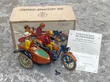 une petite moto jouet avec un homme dessus et une boîte contenant un certificat