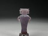 une petite figurine représentant un homme vêtu d'une chemise violette
