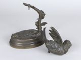 bronze sculpture of a bird on a branch with a magnifying glass