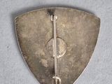 an old silver metal pin with a hook on a gray surface