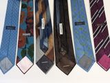several different colored ties are lined up on a white surface