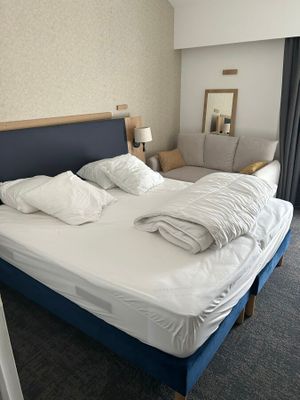 un lit avec des draps et des oreillers blancs dans une chambre d'hôtel