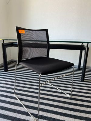 une chaise noire placée devant une table en verre