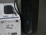 a black speaker sitting next to a box on a table