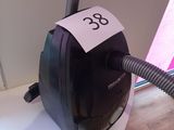 un aspirateur noir et blanc posé sur une table, sur laquelle est collé un autocollant