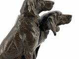 bronze statue of two dogs sitting on a rock with a white background