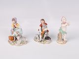 three porcelain figurines of children and a dog on a white surface
