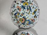 two plates with floral designs are sitting on a white surface