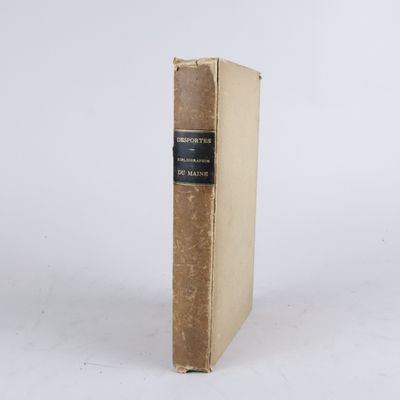 un vieux livre posé sur une table à côté d'un mur blanc